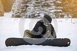 Person tieing up her snowboard in the snow