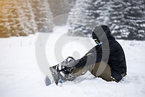 Person tieing up her snowboard in the snow