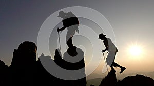 person on top of mountain. silhouette of people team hiking to top of mountain in sunset, climbing team success on the mountain.