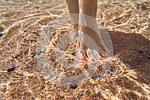 A person touches the sandy bottom with his feet and walks along the sea beach along the coastline