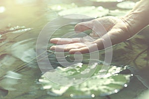 Person touches the water with his hand