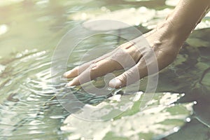 Person touches the water with his hand