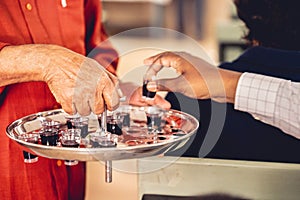 Person treats the red wine with small glasses to churchgoers to observe communion