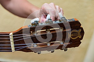 person tuning an acoustic guitar with their hand