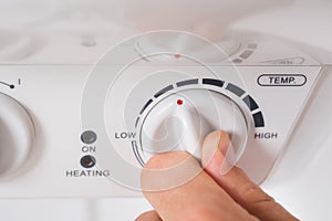 Person Turning The Knob Of Electric Boiler