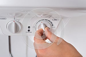 Person Turning The Knob Of Electric Boiler