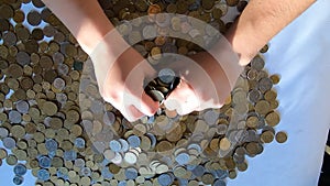 Person two hands rakes coins on table and pours spills from handful to surface