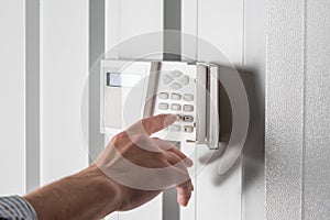 Person typing on keypad of home security alarm