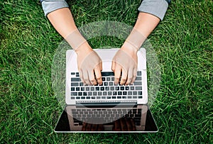 Person typing on laptop with blank screen outdoors