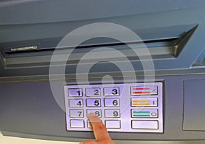 person typing the secret PIN code to access the banking services of an ATM