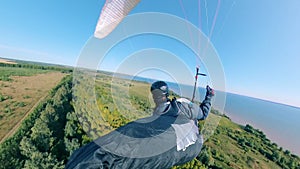 Person in uniform flying with paraplane over trees.