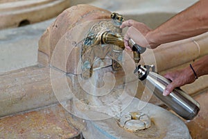 Person uses the thermal spring water fountain of Vichy Celestins