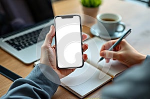 Person Using AI Assistant on Smartphone While Taking Notes at a Workspace