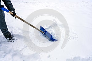 Person are using a Blue snow shovel/spade outdoors removing the deep snow during snowy weather.