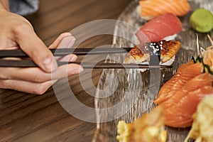 Person using chopsticks for eating sushi at a restaurant