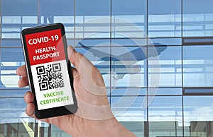 Person using digital health passport app in mobile phone with an unidentifiable QR code for travel during covid-19 pandemic.