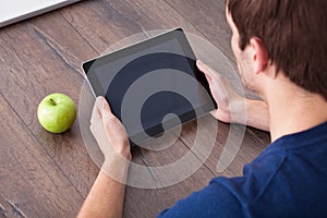 Person using digital tablet besides green apple