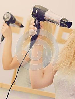 Person using hair dryer on blonde hairdo