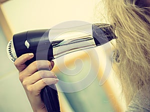 Person using hair dryer on blonde hairdo
