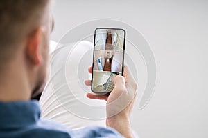 Person Using Home Security System On Mobile Phone