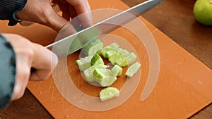 Person using knife on a cucumber on wooden cutting board