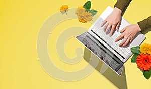 Person using a laptop computer with autumn flowers