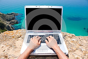 Person using laptop by the sea