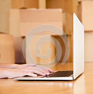 Person using notebook with cardboard boxes on background