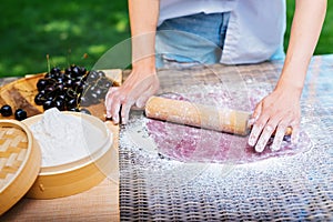 Person using rolling pin on table to roll out dough. Mochi asian dessert