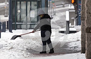 Person using shovel and cel phone during snow storm