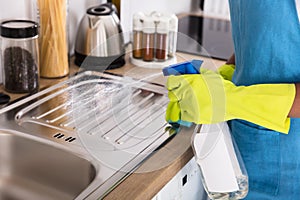 Person Using Spray Bottle For Cleaning Kitchen Sink