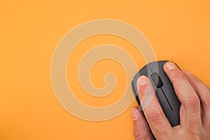 Person using wireless computer mouse on yellow background