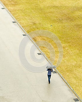 A person is walking down a sidewalk with an umbrella