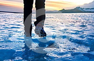 Person walking on glacier ice surface wearing crampons