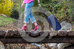 Person walking on old wooden bridge pulling Travel Suitcase