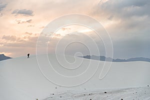 A person walking on a sand dune at White Sands National Monument in Alamogordo, New Mexico.