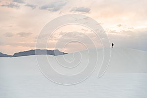A person walking on a sand dune at White Sands National Monument in Alamogordo, New Mexico.