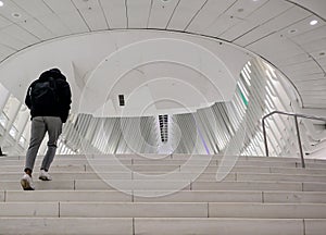person walking up stairs at oculus transportation hub manhattan (fulton street, world trade center) man dark clothes