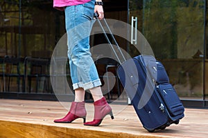 Person walking on wooden terrace pulling Travel Suitcase