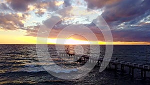 Person walks on pier at sunset