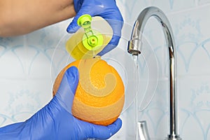 Person washes fruit with eco soap for washing in a kitchen with blue walls. Decontamination and disinfection of products