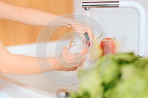 Person Washing a Glass in Kitchen Sink