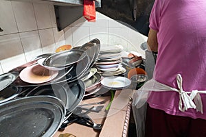 Person washing pile of dirty plates in a mundane task in a traditional restaurant in Asia