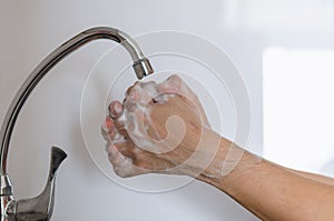 Person washing and rubbing with soap in all area of hands, fingers and wrists photo