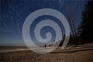 Person watching the stars with star trail effect on a beach, near Southampton, Ontario