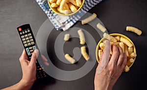 Person watching a TV and eat snacks, corn puffs