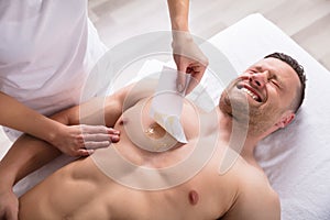 Person Waxing Man`s Chest With Wax Strip