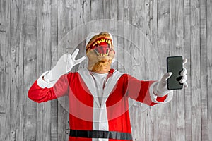 Person wearing a dinosaur mask showing a V peace sign isolated on a gray wooden background