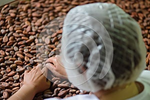 person wearing a hairnet checking cocoa beans