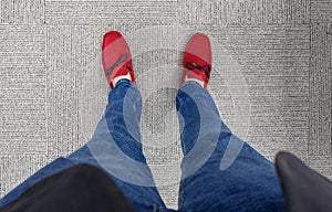 A person wearing jeans with bright classy red loafer shoes with black laces